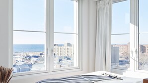 A bedroom with a large bed, a view of the city, and a window with curtains.