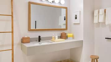 Un baño moderno con un espejo grande, un lavamanos con dispensador de jabón y un perchero para toallas.