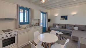 Eine moderne Küche mit weißen Schränken, einer blauen Tür und einem Essbereich mit einem runden Tisch und Stühlen.