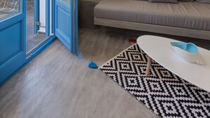 Ein modernes Wohnzimmer mit einem grauen Sofa, einem gemusterten Teppich und einem weißen Couchtisch.