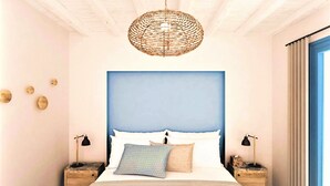Ein Schlafzimmer mit einem großen Bett, einem blauen Kopfteil, zwei Nachttischen mit Lampen und einer gewebten Deckenleuchte.