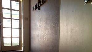 A hallway with a patterned rug, a door with a view to the outside, and a textured wall with a wooden shelf. - Little Cottage in Flagstaff (Flagstaff)