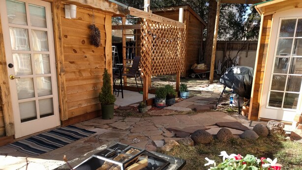 A wooden cabin with a stone patio, outdoor seating, and a grill. - Little Cottage in Flagstaff (Flagstaff)
