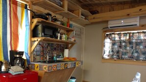 A compact kitchen with a microwave, coffee maker, and colorful tiles. There is a window with patterned curtains and a red cabinet. - Little Cottage in Flagstaff (Flagstaff)