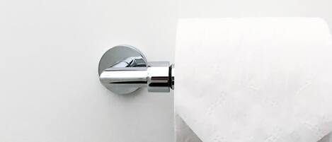 Un sujetapapel higiénico con un rollo de papel higiénico sobre una superficie blanca.