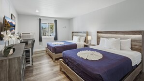 A hotel room with two beds, a desk, and a window with curtains.