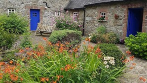 A stone building with a blue door and a bench in front. - Restored Historic Cottage in County Kilkenny (Carrickshock)