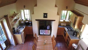 A compact kitchen with a dining table, chairs, and basic appliances. - Restored Historic Cottage in County Kilkenny (Carrickshock)