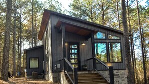A cabin with a stone foundation, wooden exterior, and a staircase leading to a porch. - Somewhere With You -Features a hot tub & fire pit; accommodates 2 to 4 guests.   (Broken Bow)