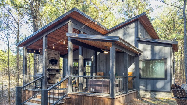 A cabin with a wooden deck, stone fireplace, and a large window. - Somewhere With You -Features a hot tub & fire pit; accommodates 2 to 4 guests.   (Broken Bow)