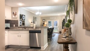 A modern kitchen with white cabinets, a stainless steel dishwasher, and a granite countertop. - 2103 Golf View Towers Lazy Bears Den (Pigeon Forge)