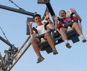 Zwei Personen schaukeln auf einer Schaukel in einem Freizeitpark.