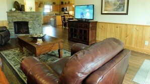 A living room with a fireplace, leather sofa, coffee table, and a television.