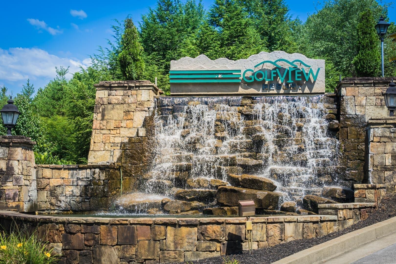 A stone wall with a waterfall and a sign for Golfview Resort.