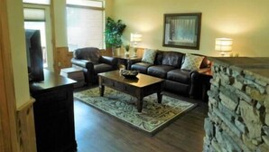 A living room with a sofa, coffee table, and a stone wall.