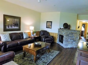 Ein Wohnzimmer mit Kamin aus Stein, Ledersofas, einem Couchtisch und einem gemusterten Teppich.