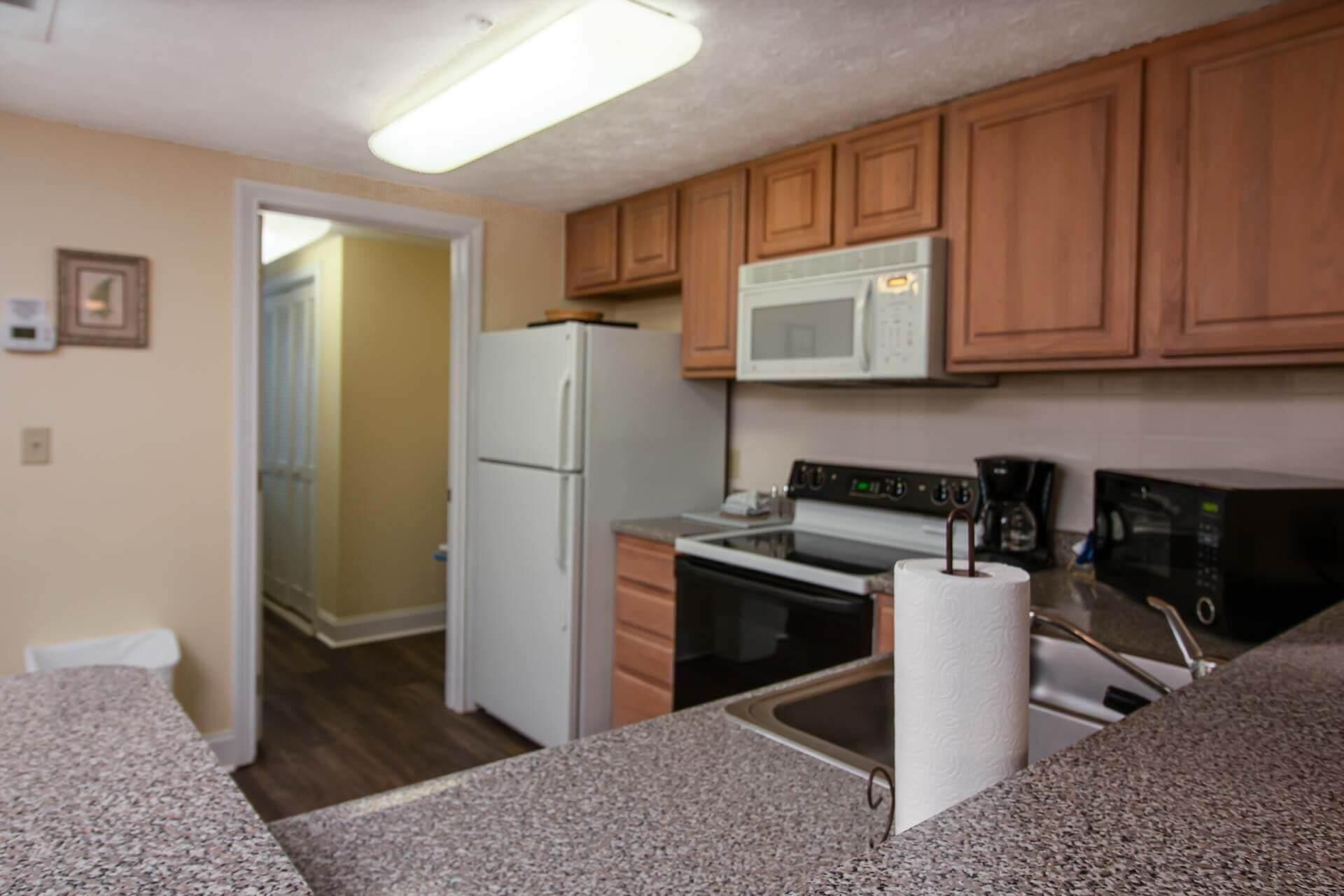 A compact kitchen with a refrigerator, microwave, stove, and sink.