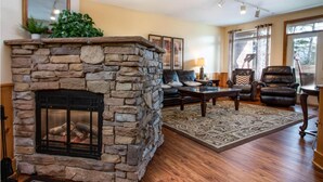 A stone fireplace with a fire, a leather sofa, a coffee table, and a patterned rug in a living room. - 3107 Golf View Hillcrest Garden Terrace (Pigeon Forge)