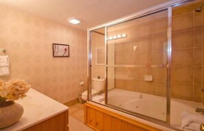 A modern bathroom with a glass-enclosed shower, a bathtub, and a vanity with a flower vase.