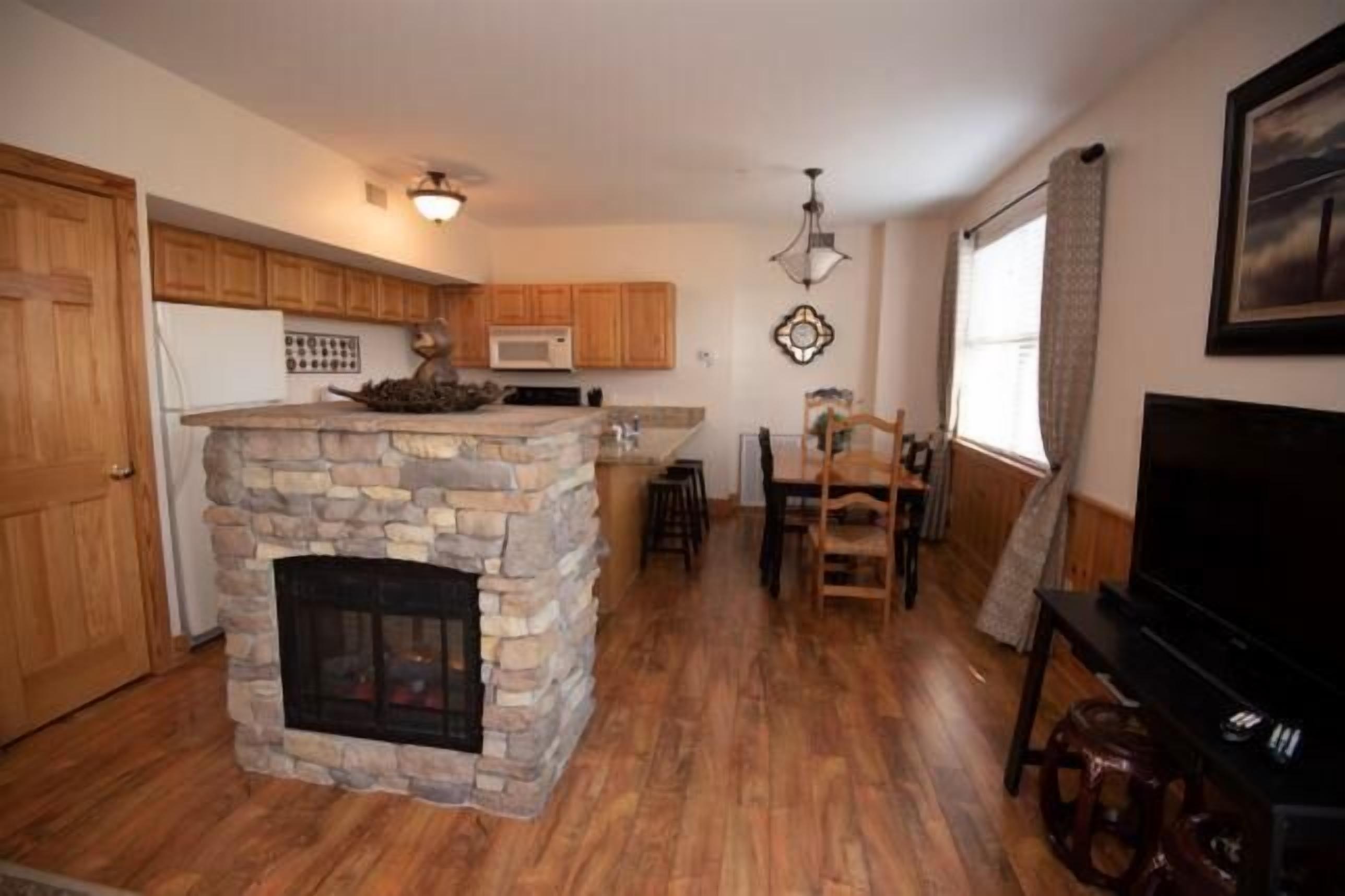 A kitchen with wooden cabinets, a stone fireplace, a microwave, and a dining area with a table and chairs.