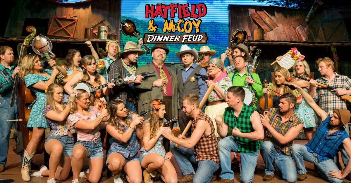 A group of people in a rustic setting with a sign reading "HATFIELD & MACOY DINNER FEUD".