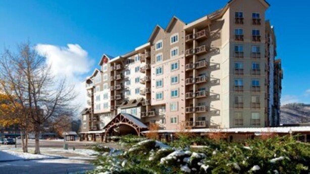 Ein mehrstöckiges Hotel mit Balkonen, einem überdachten Eingang und verschneiter Landschaft im Hintergrund.