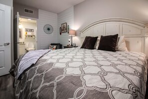 Een slaapkamer met een bed, nachtkastje, lamp en een muur met decoratieve objecten.