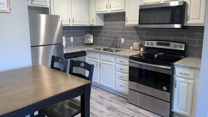 A modern kitchen with white cabinets, stainless steel appliances, and a granite countertop. - 1404 Golf View Towers Smoky Mtn Bearadise (Pigeon Forge)