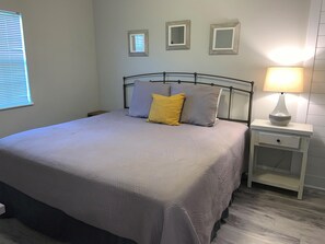 A neatly made bed with a grey bedspread and two pillows, a bedside table with a lamp, and three framed mirrors on the wall. - 1404 Golf View Towers Smoky Mtn Bearadise (Pigeon Forge)