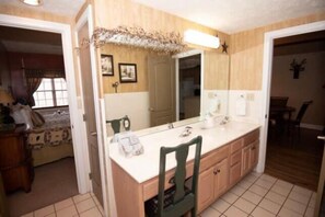 A bathroom with a large mirror, a sink, and a chair.