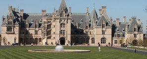A large, historic building with a symmetrical facade, multiple chimneys, and a central entrance.