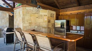 A kitchen with a stone backsplash, a refrigerator, and a grill. - 839a Golf View Cabins Rockin' Robin (Pigeon Forge)