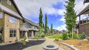 Een woongebied met huizen van steen en hout, een centraal pad en een vuurkorf.