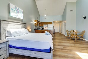 A bedroom with a bed, bedside tables, a desk, and a chair. There is a kitchenette in the background. - 4 Mi to Cherry Grove Beach: Studio w/ Pool Access (Little River)