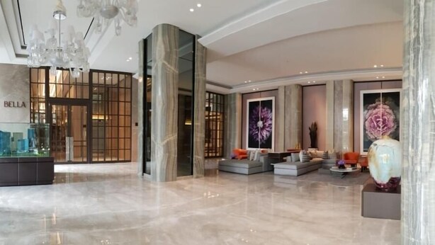 A spacious lobby with a marble floor, a seating area with sofas and a coffee table, and a large decorative vase.