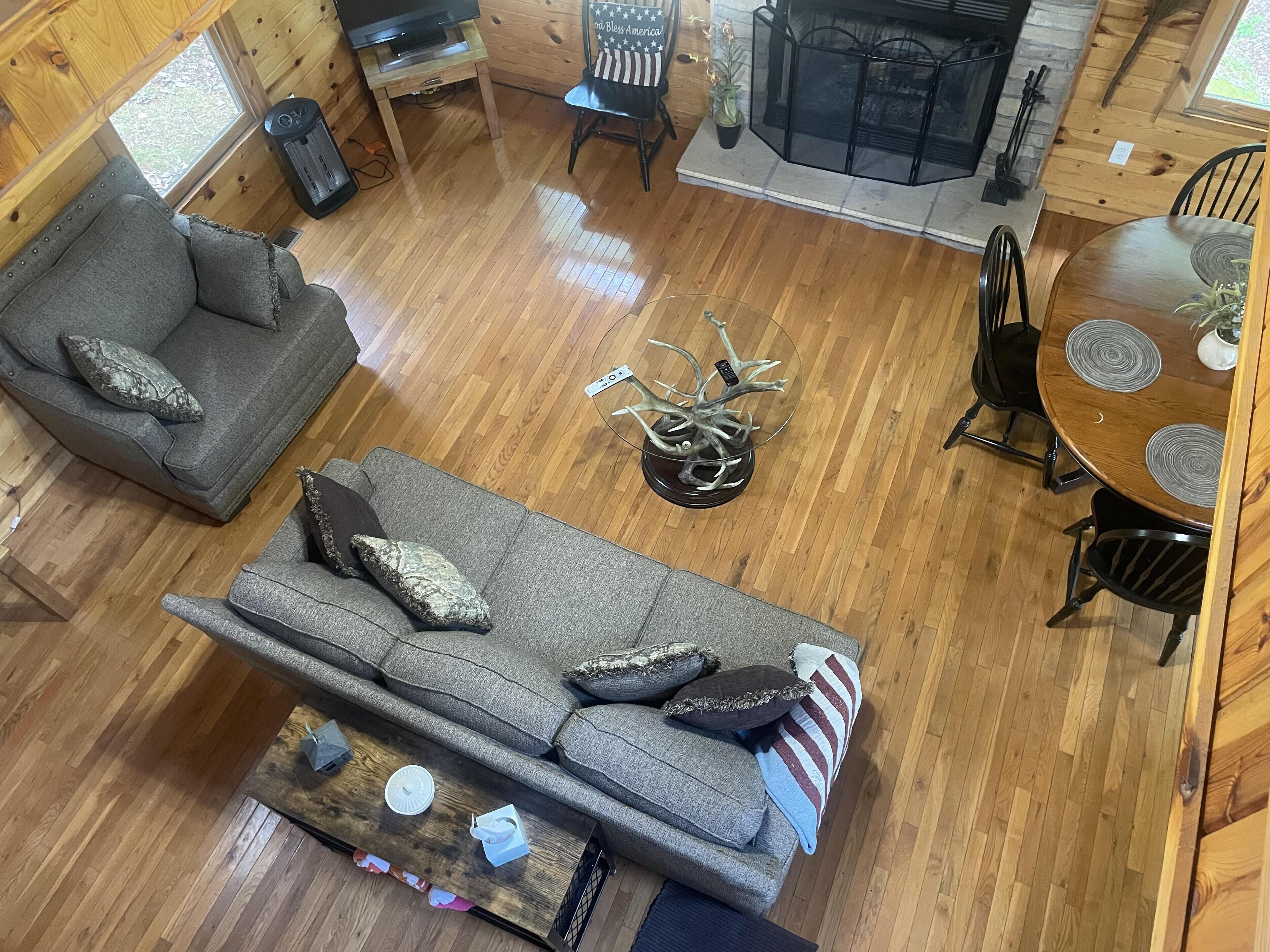 A cozy cabin interior with a sofa, a coffee table, a dining table, and a fireplace.