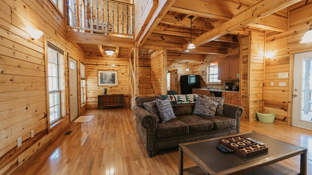 L’intérieur d’un chalet en bois comprend un salon, un balcon et un coin cuisine.