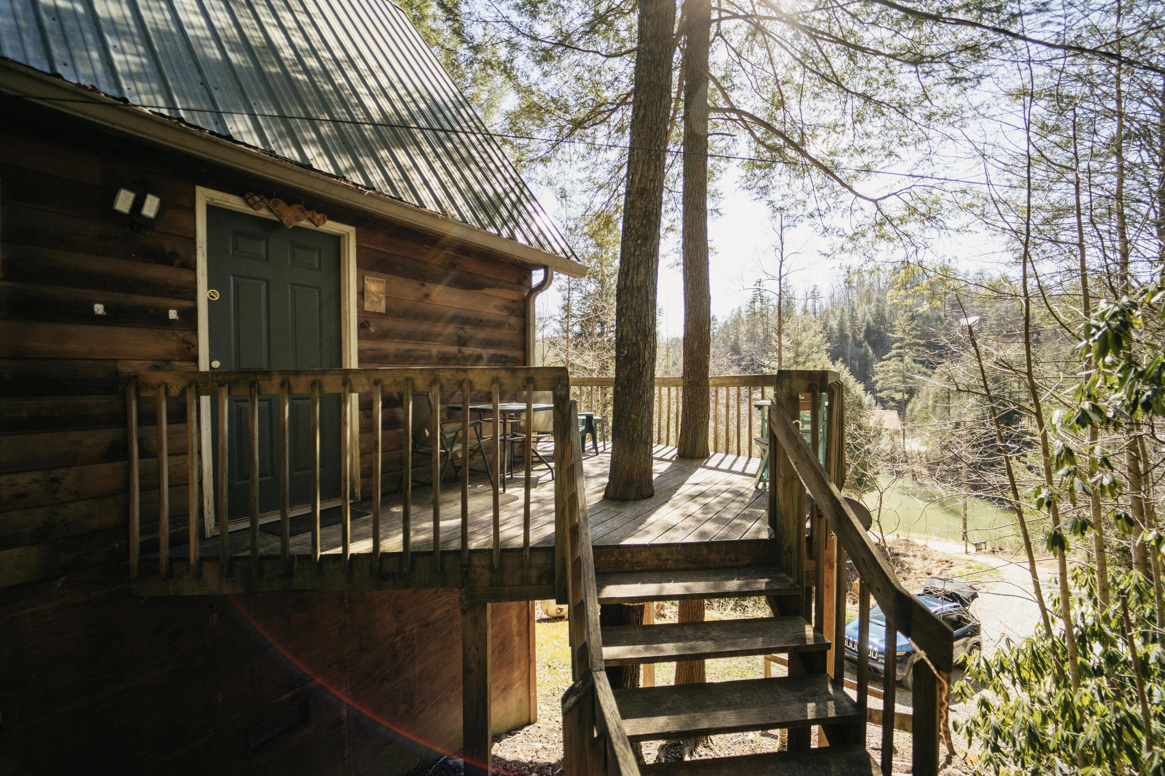 A wooden cabin with a porch and steps leading to a deck.