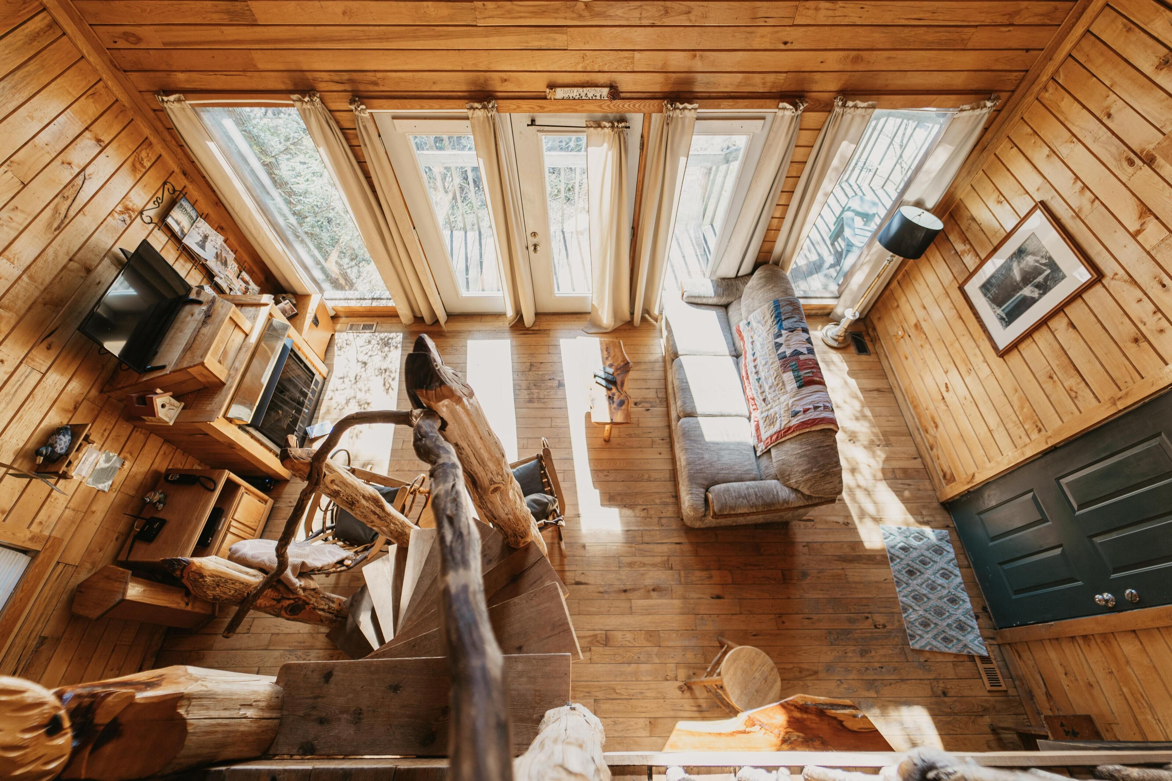 Een blokhutinterieur met houten wanden, een open haard, een bank en een eettafel.