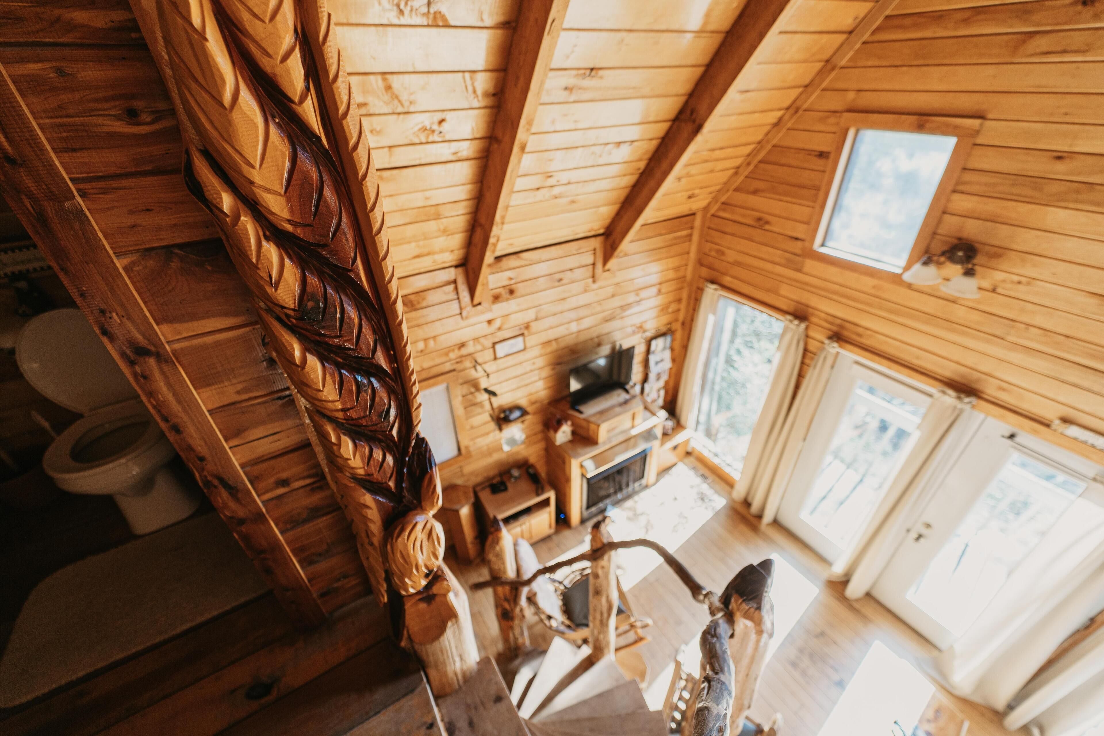 A wooden interior with a staircase, a television, and a window.