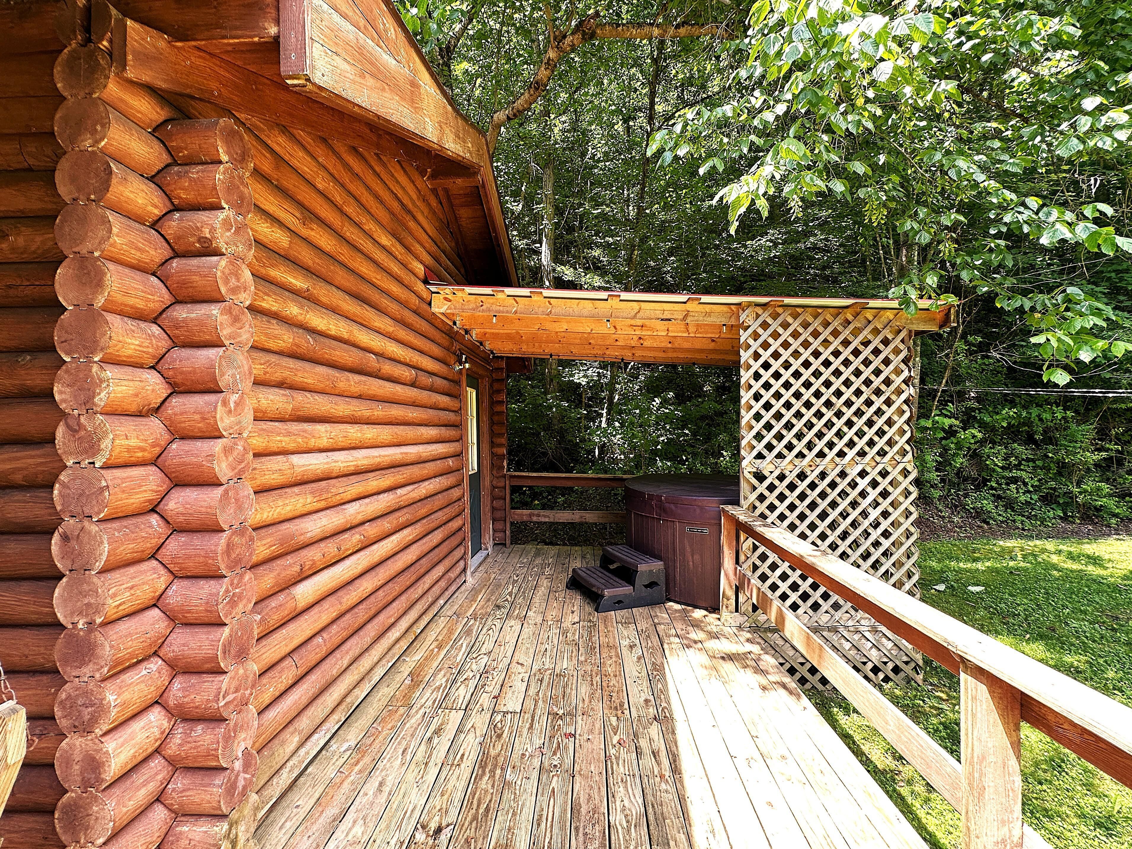 Una cabaña de madera con terraza y valla enrejada.