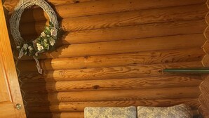 L’intérieur d’une cabane en bois, avec un lit, une porte et une couronne décorative accrochée au mur.
