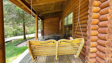 A log cabin with a porch, a swing, and a dining area.
