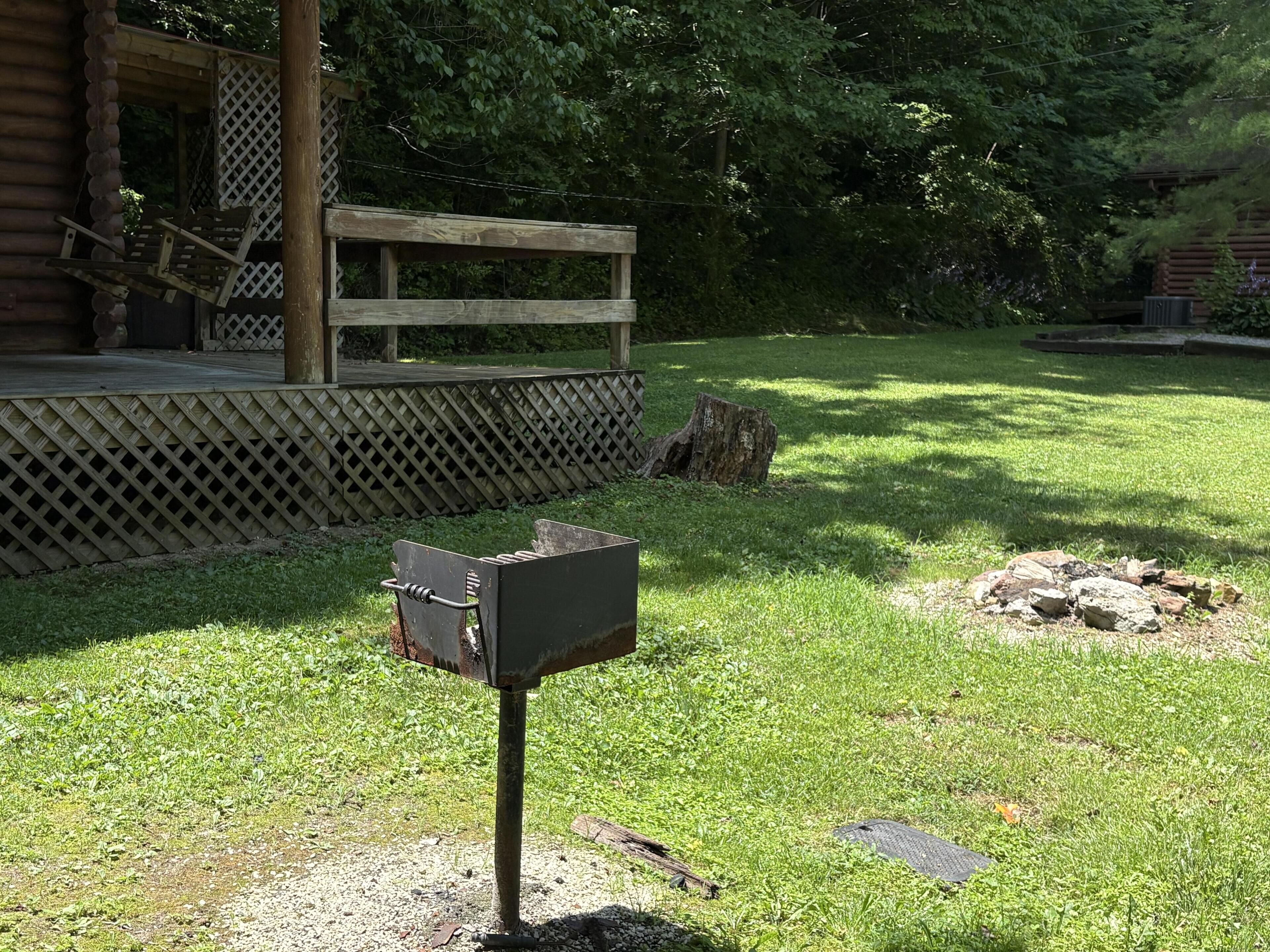 A wooden mailbox in a grassy area with a wooden deck and a wooden fence in the background.