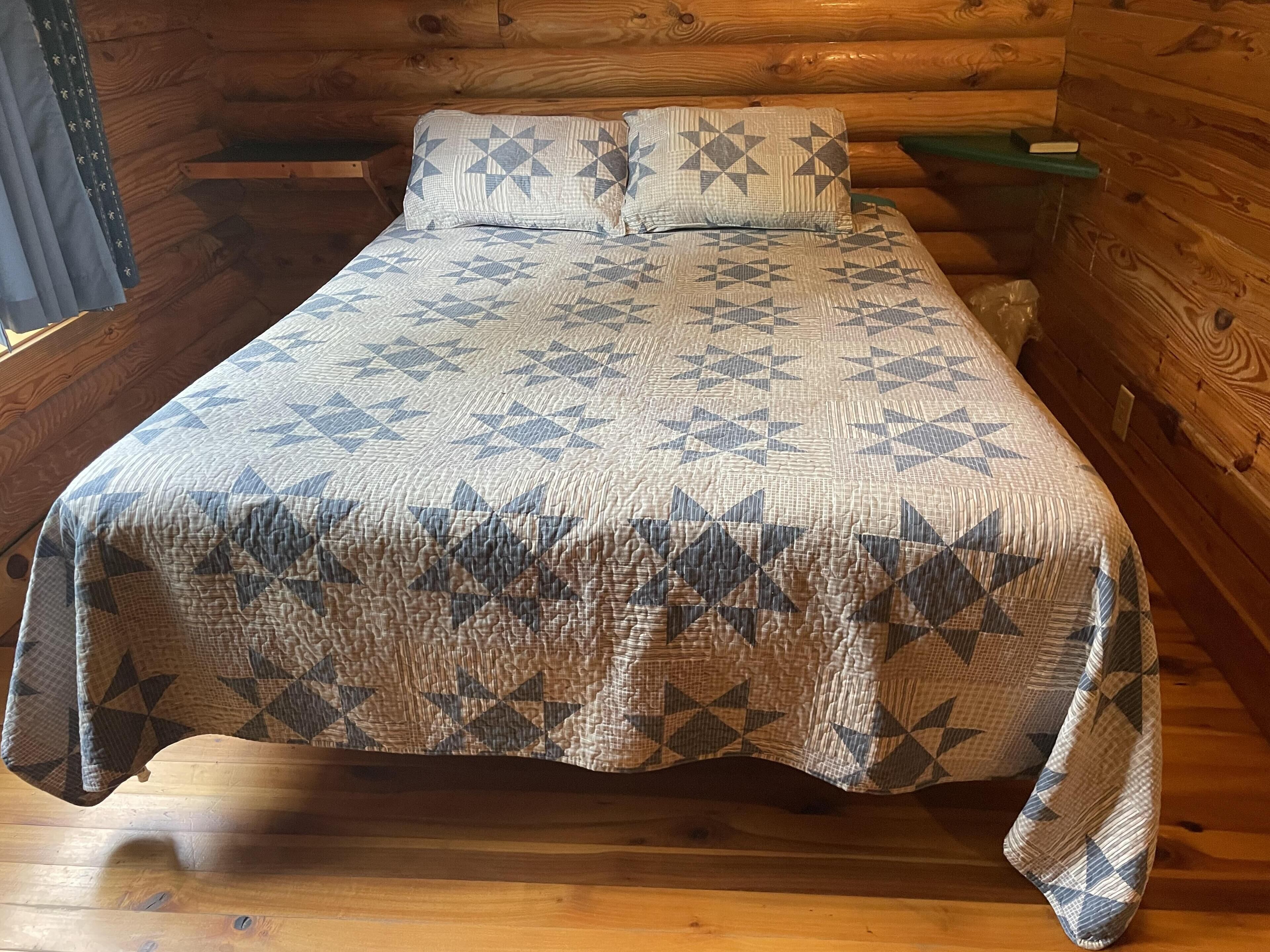 Een bed met een deken met een geometrisch patroon in een blokhutkamer.