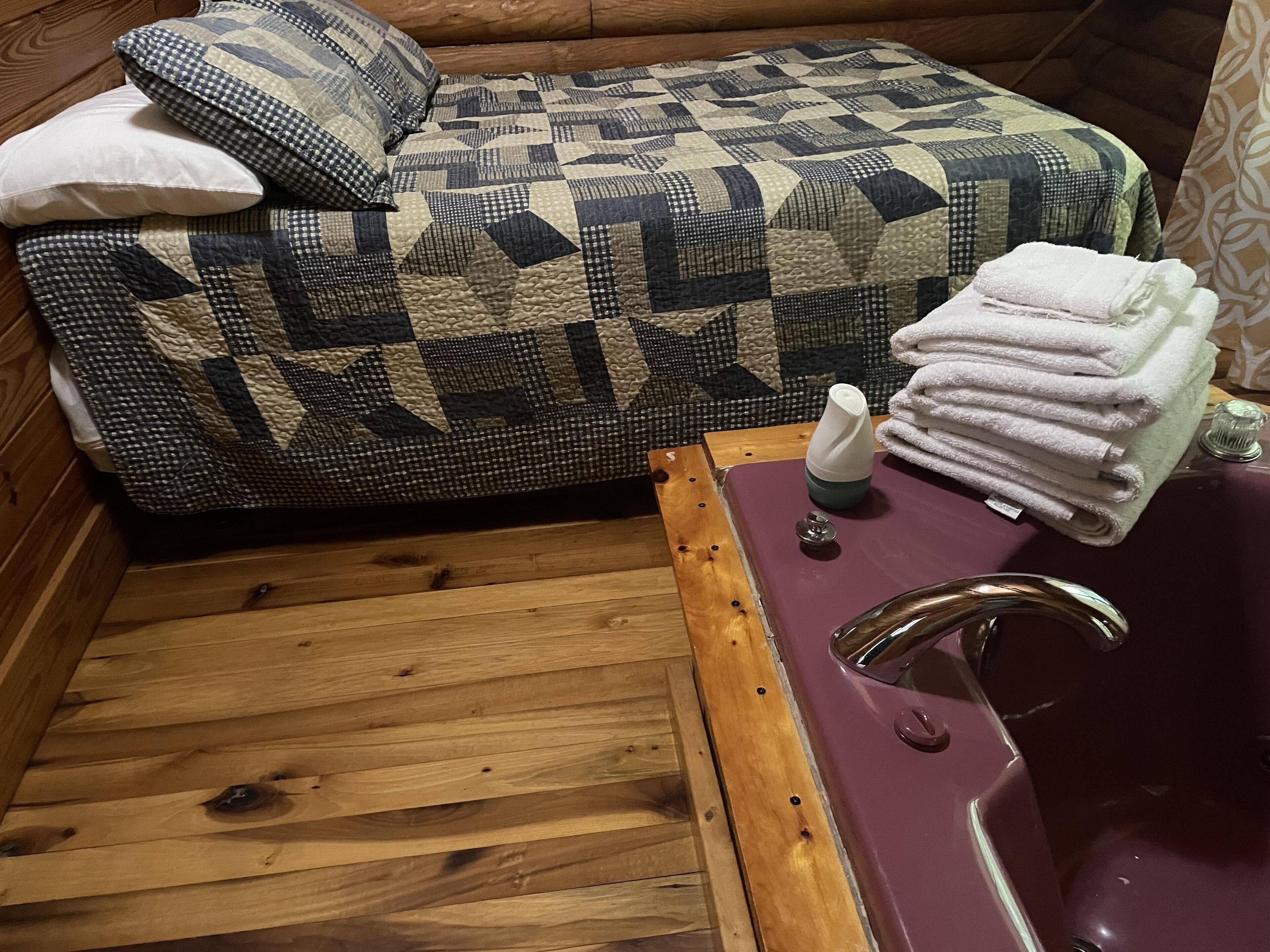 Un plancher en bois, une baignoire violette, un canapé à carreaux et une pile de serviettes.