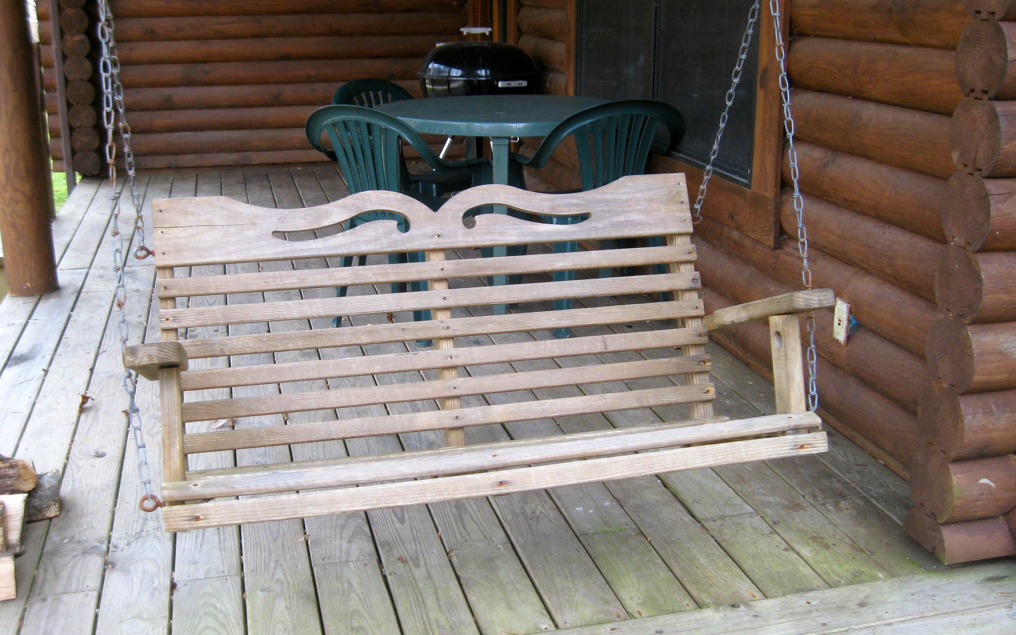 A wooden bench with a curved backrest on a wooden deck.
