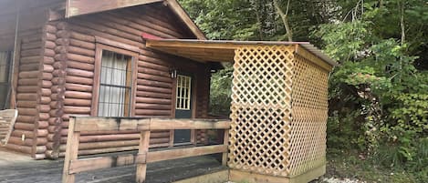 A log cabin with a wooden deck and a lattice structure.