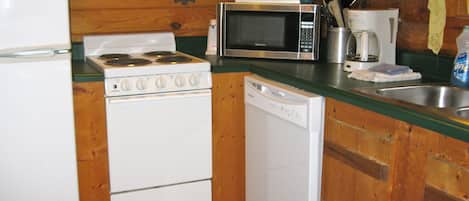 A compact kitchen with a stove, microwave, dishwasher, and a refrigerator.