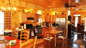 A wooden cabin interior with a kitchen, dining area, and a living room. - Spacious cabin with Hot Tub and wood burning fireplace and wi-fi (Campton)